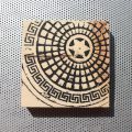 Copenhagen manhole cover artwork on wood block